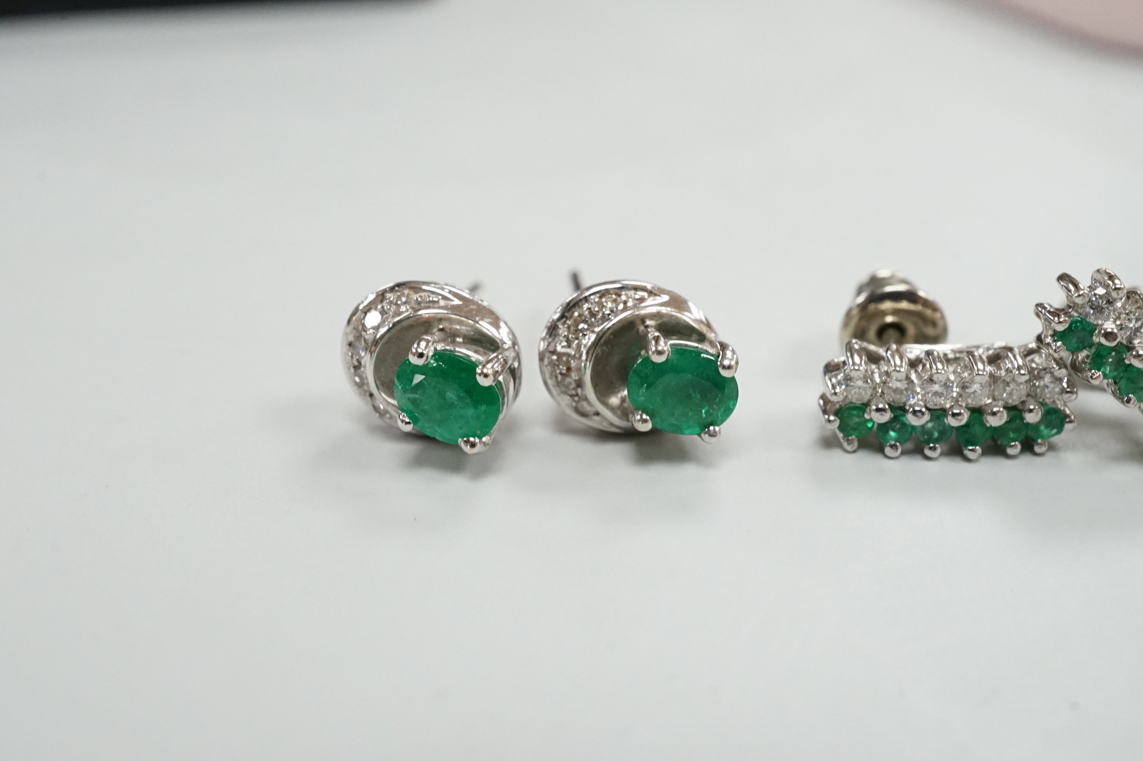 Two moderns pairs of emerald and diamond set ear studs, including white metal two row and 14k oval cut single stone and diamond chip, 7mm, gross weight 5.6 grams.